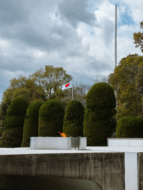Japanese flag above the hiroshima peace flame in Hiroshima peace park