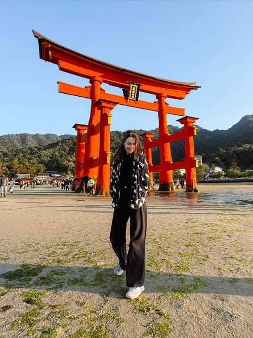 nele standing on the sand in front of miyajima torii gate at low tide