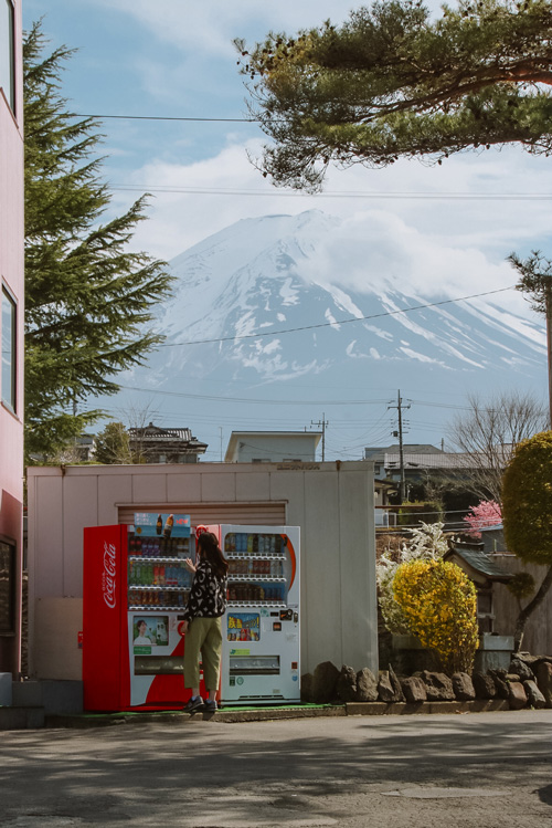 nele standing in front of a vending machine with mount fuji in the background