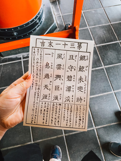 nele holding a japanese fortune telling paper at sensoji shrine in tokyo