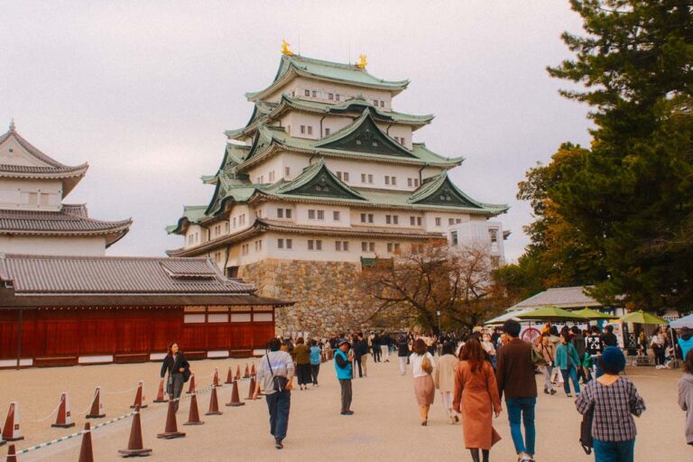 nagoya castle on a cloudy day with a large crowd in front of it
