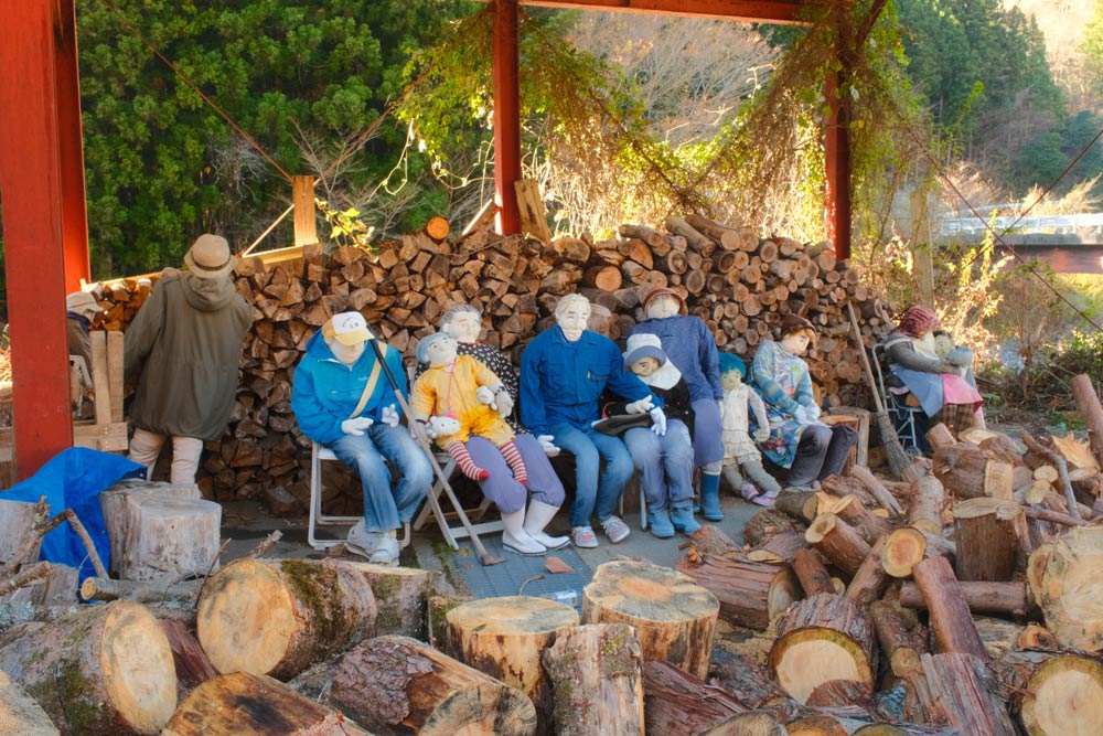 scarecrows sitting near chopped wood on a sunny day in nagoro scarecrow village on shikoku island