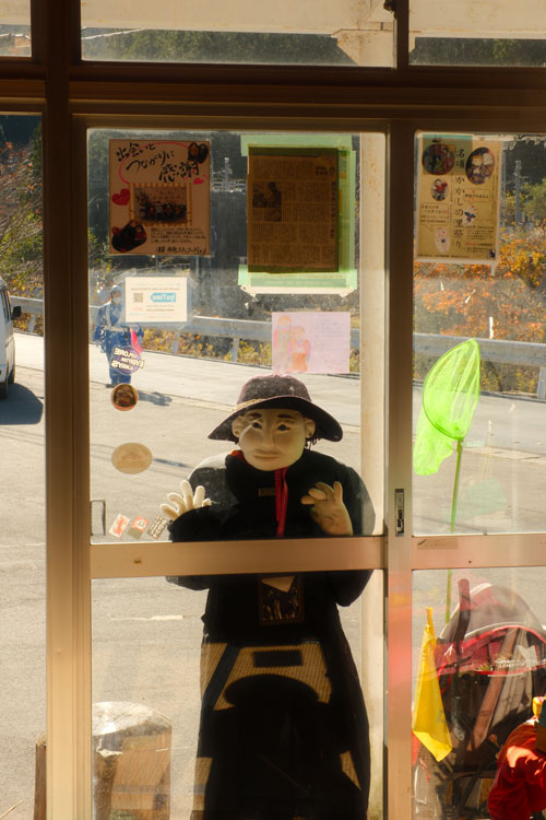 scarecrow in nagoro looking through the windows of the tourism information centre