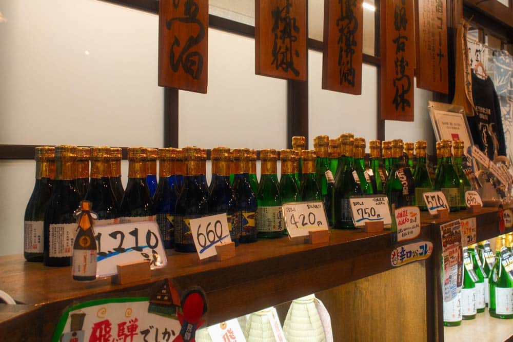 bottles of sake lined up with price signs in hida furukawa sake district